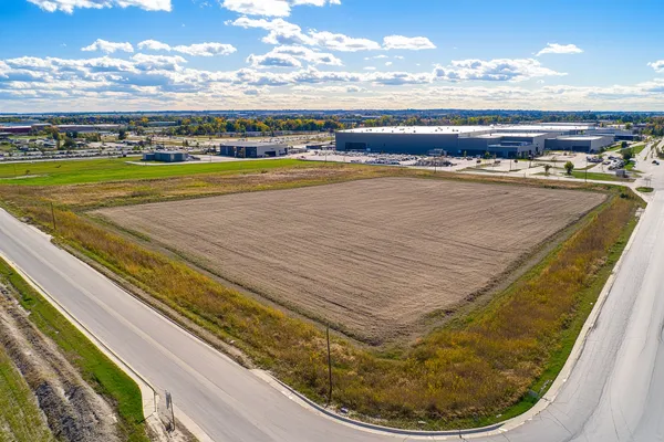 Aerial view of cleared commercial land parcel near warehouses